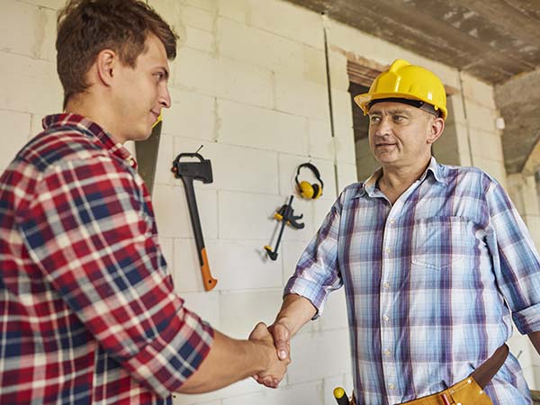 Deux hommes travaillant dans le secteur du bâtiment se serrent la main, ce geste représente l'accord d'un contrat d'embauche