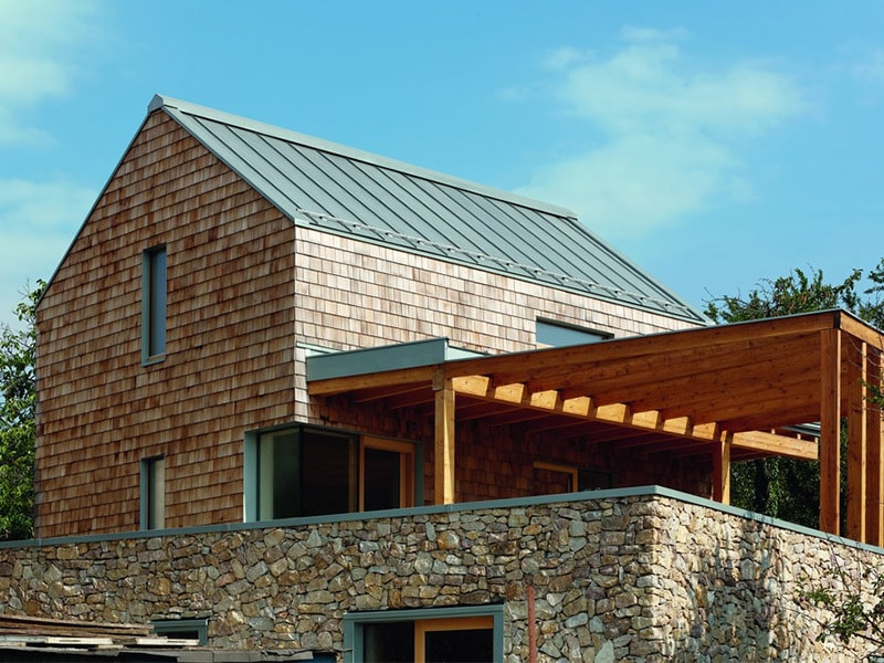 Couverture et détails architecturaux en zinc pour souligner l'harmonie de matériaux naturels d'une maison familiale - Batiweb